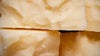 Close-up of several blocks of Parmesan cheese, showcasing their rough and textured surfaces with flaky layers. The cheese is a pale yellow color, highlighting its crumbly and aged appearance.