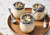 Three jars of Chocolate Topped Peanut Butter Yogurt cup dessert on a wooden plate with spoons.