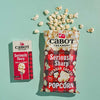 Cabot Popcorn and Mac and Cheese on teal background with popcorn spilling out of the bag