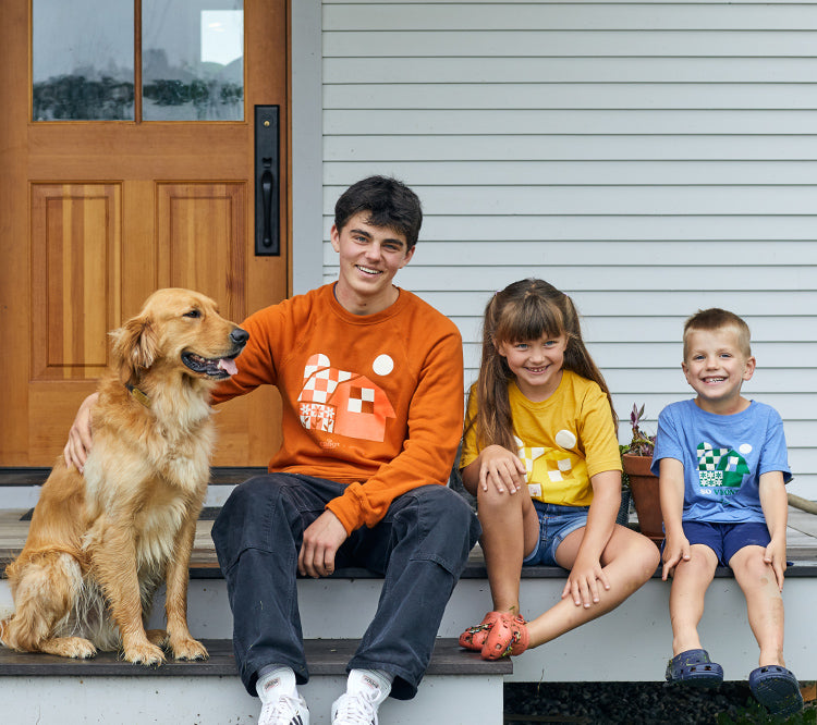 people & a golden retriever sitting on a porch wearing cabot merchandise.