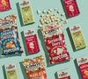 Cabot Popcorn and popcorn spilling out of the bag and mac and cheese in boxes on green background
