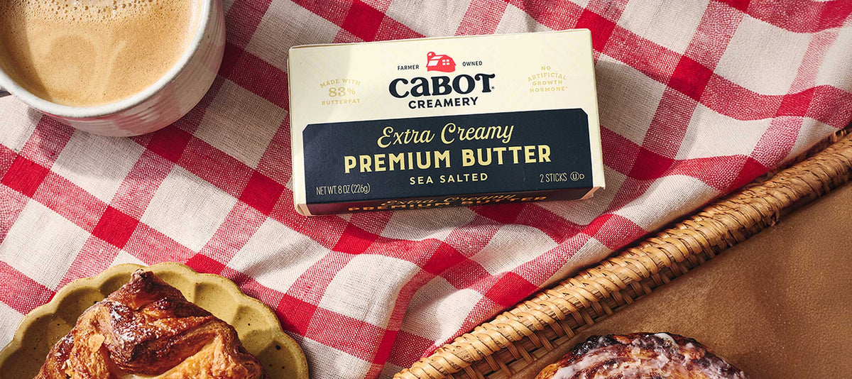Cabot Butter on a plaid tablecloth with pastries and coffee.