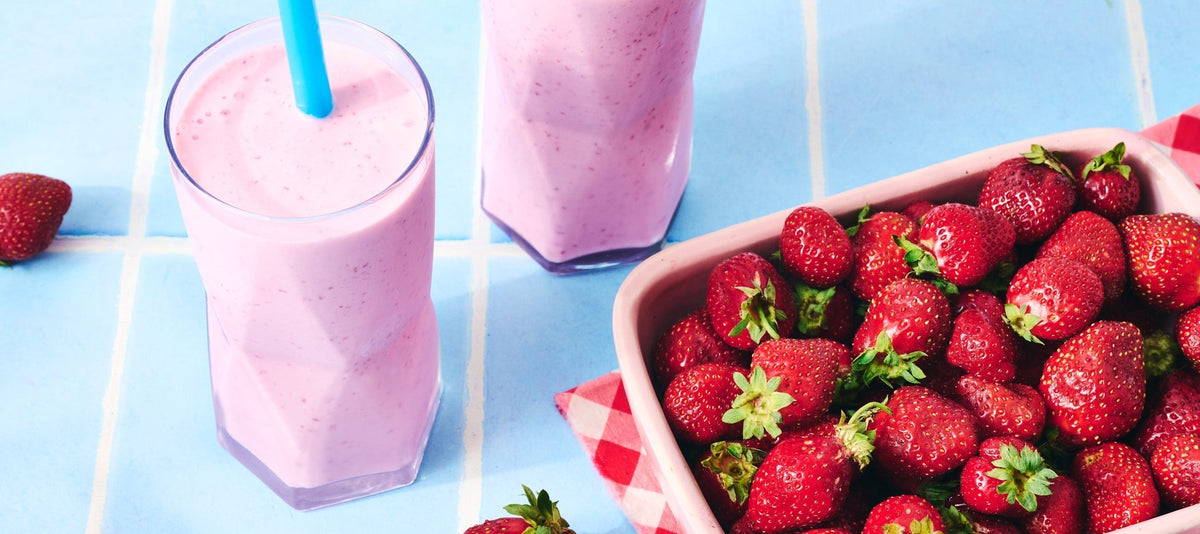 Strawberry Smoothie on a blue background with a dish of strawberries