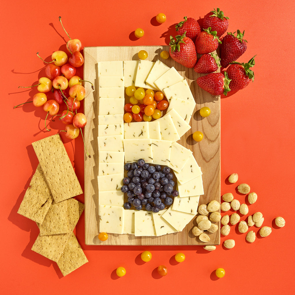 a cheese board in the shape of a B on an orange background