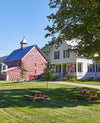 Liberty Hill Farm in Vermont barn and bed and breakfast in the foreground with green grass and blue skies.