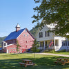 Liberty Hill Farm in Vermont barn and bed and breakfast in the foreground with green grass and blue skies.