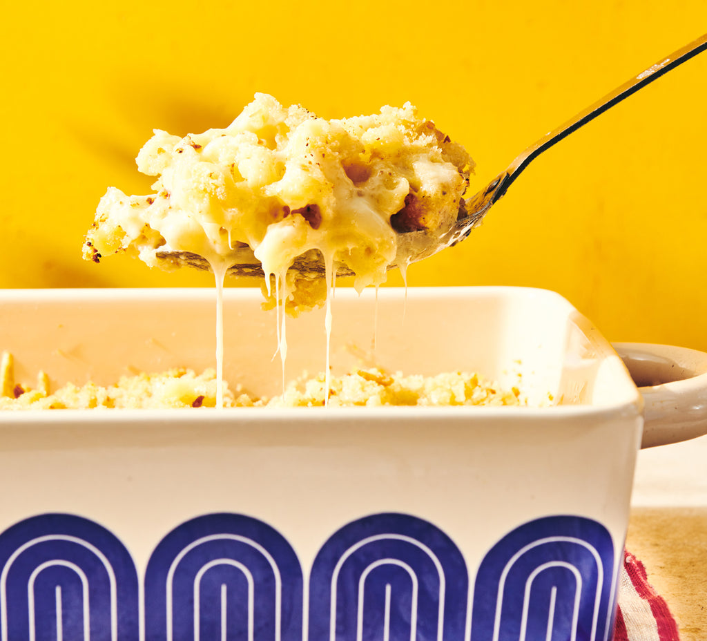gooey mac and cheese in a baking dish being spooned up