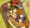 Cheese board on a yellow background featuring a variety of B Corp food items