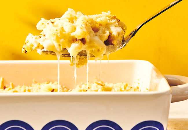 gooey mac and cheese in a baking dish being spooned up