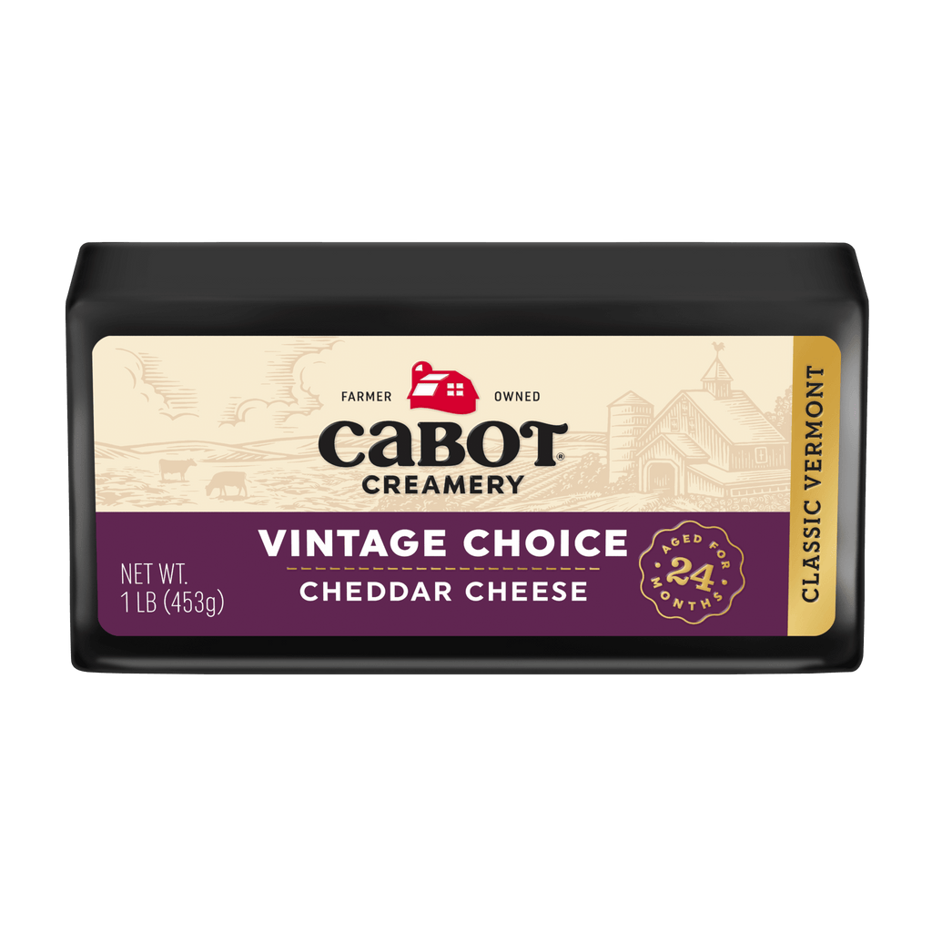 Cabot Creamerys Vintage Choice Cheddar Cheese, aged 24 months, comes in a dark package with a cream label showing red barn and farm images. Weighing 1 lb (453g), it proudly displays the Classic Vermont label.