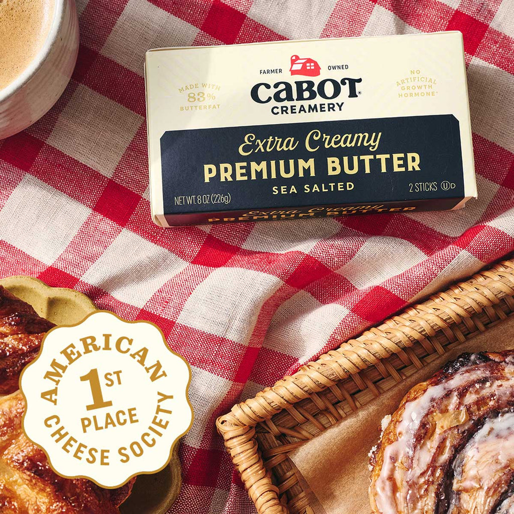 Box of Cabot Creamery Extra Creamy Premium Butter on a red and white checkered tablecloth with pastries.