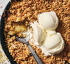 Apple crisp dessert with ice cream in a skillet.