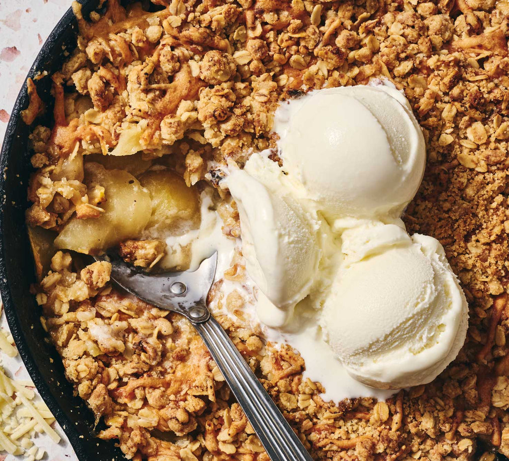 Apple crisp dessert with ice cream in a skillet.