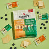 Cabot Creamery Sharp & Gouda Variety Pack snack-size cheese bars, crackers, and blueberries are displayed on a light green background with visible cheese slices and opened packs of Gouda and Vermont Sharp Cheddar around the main package.