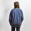 A person seen from behind wearing an oversized blue heavyweight Cheddar Crewneck sweatshirt.