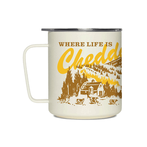 Introducing the “Where Life is Cheddar Insulated Mug” by Miir—a cream-colored camp mug with a handle, adorned with yellow and brown artwork depicting a cabin, cows, trees, and rolling hills. The playful text “WHERE LIFE IS Cheddar,” with “Cheddar” in bold script font, honors the classic charm and heritage of the Cabot cooperative.