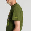 A person wearing the New Duds “Where Life is Cheddar” T-shirt in green, featuring yellow Cabot Creamery sleeve print, shown from a side view against a plain background.