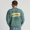 A person is seen from behind wearing the New Duds Life’s Better With Butter Crewneck, a green sweatshirt featuring a butter graphic and the text: “Life’s Better With Butter, Cabot Creamery, Est. 1919, Vermont, USA.”.