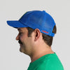 A man in a green shirt with a mustache, shown in profile against a plain light background, wears the New Duds Vintage Cabot Cow Graphic Mesh Trucker Hat.