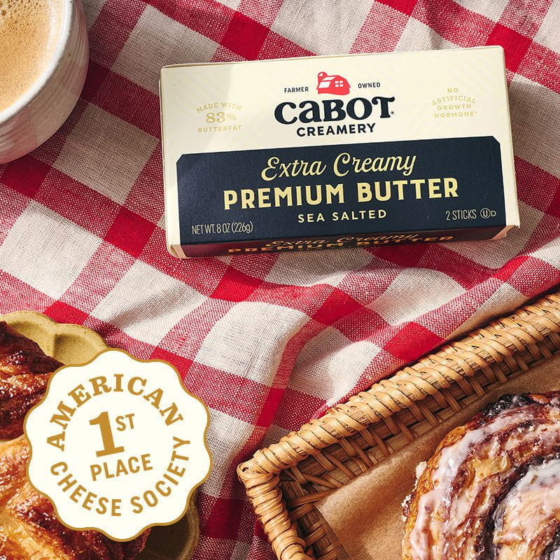 Box of Cabot Creamery butter on a red and white checkered tablecloth with pastries and a cup of coffee.