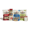 The Cabot Creamery Cozy Care Package features an irresistible collection of cheese snack sticks, cocoa powder, a mug, maple candy, and chocolate cookies—all beautifully arranged on a white background—making it the perfect gift box or care package for any occasion.