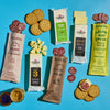 The Grazing Gift Box from Cabot Creamery featuring an assortment of premium cheeses, sliced salami, round crackers, and a jar of mustard spread out on a blue background.