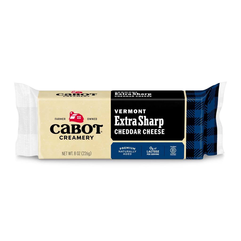 An 8 oz package of Cabot Creamery Extra Sharp Cheddar Cheese, featuring a blue and black plaid design, farmer-owned heritage, naturally aged flavor, and lactose-free—premium cheddar from the East Coast.