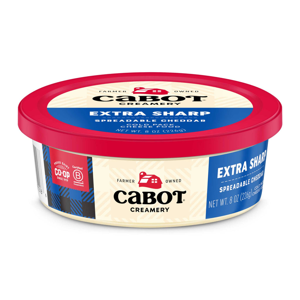 An 8 oz (226g) round container of Cabot Creamery Extra Sharp Cheddar Cheese, featuring a red lid, blue accents, and labeled Farmer Owned.