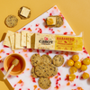 A marble board features Cabot Creamery Habanero Cheddar Cheese slices, whole-grain crackers, golden cherry tomatoes, and honey with a dipper—all on a yellow background. Enjoy this bold, lactose-free snack combo!.