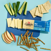 Cabot Creamery Mild Cheddar Cheese, sliced and lactose free, is served with cucumber sticks, gluten-free crackers, pretzel sticks, and apple slices on a blue background.
