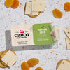 Packaged Cabot Creamery Pepper Jack cheese on a terrazzo countertop with crackers and dried apricots.