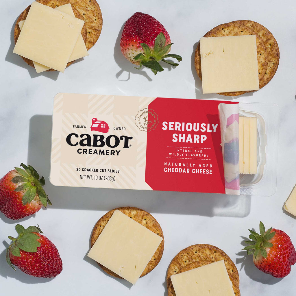 Cabot Creamery Seriously Sharp cheese packaging with crackers and strawberries on a white background