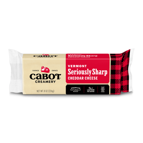 An 8 oz block of Cabot Creamery Seriously Sharp Cheddar Cheese features a yellow and red label with black plaid accents and product details on a white background.