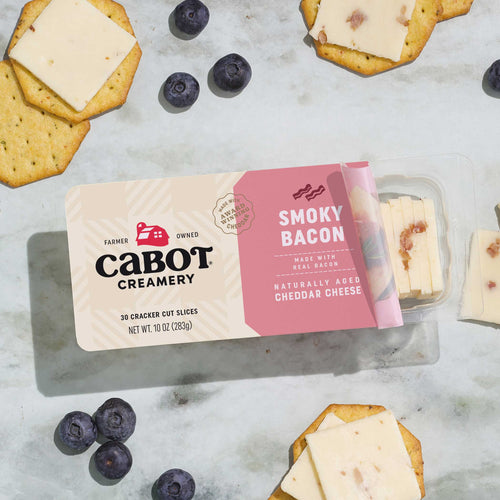 Cabot Creamery Smoky Bacon cheese packaging with crackers and blueberries on a marble surface