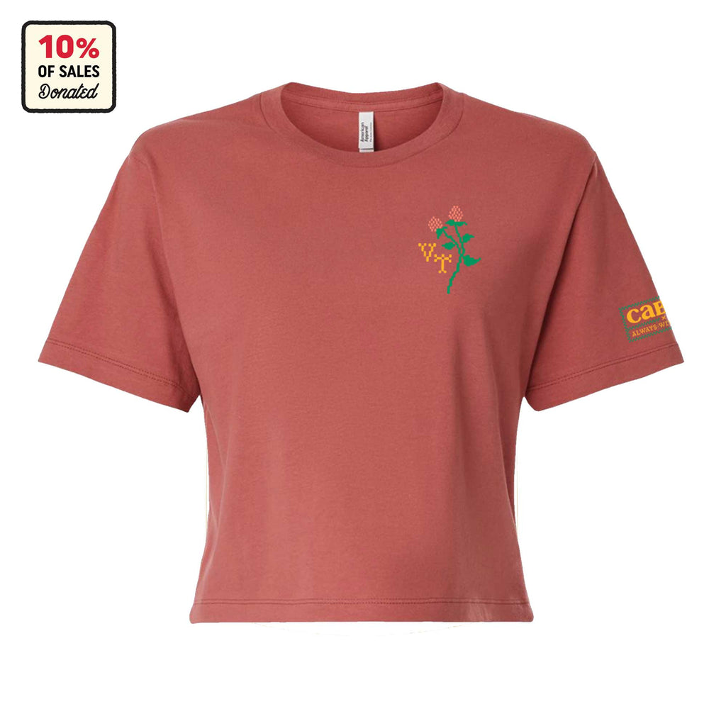 The Cabot x Always With Honor Cropped T-shirt by New Duds is made from garment-dyed cotton in dusty rose, with a floral graphic on the left chest, care text on the right sleeve, and a 10% of sales donated label in the top left corner.