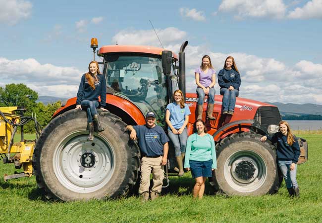 A Cabot farm family posing in front of a big orange tractor in Vermont.