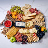 Assorted charcuterie board with meats, cheeses, fruits, and crackers on a white marble surface.