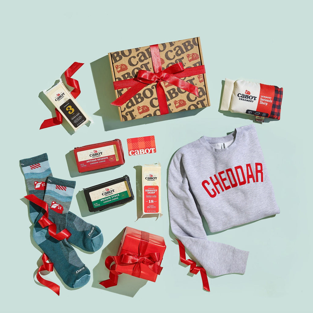 Collection of gift items including a sweater, socks, and boxes on a light blue background