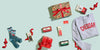 Collection of gift items including a sweater, socks, and chocolate bars on a light blue background.