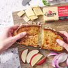 Cabot Seriously Sharp Cheese with a Grilled Cheese sandwich on a cutting board with apples and onions