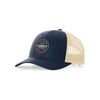 The Committed to Quality Trucker Hat by select design is navy blue and beige with a circular Cabot Creamery patch reading Premium Quality Crafted to Last. It features an adjustable snap back, a mesh rear, and honors Cabot farmers dedication to quality.