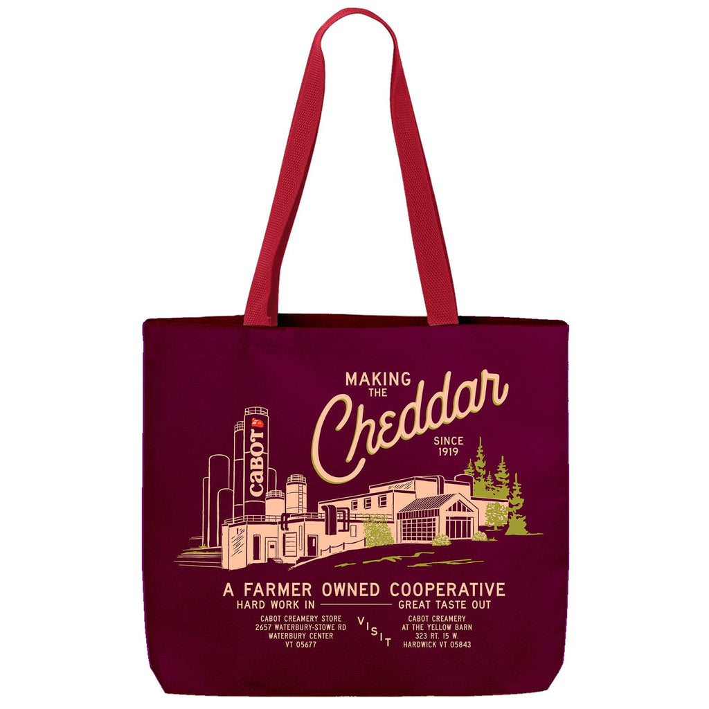 Carry your co-op pride with the Making the Cheddar Canvas Tote by New Duds, featuring a Cabot Creamery illustration and Making the Cheddar since 1919 on maroon canvas with red handles. Farmer owned, Vermont.