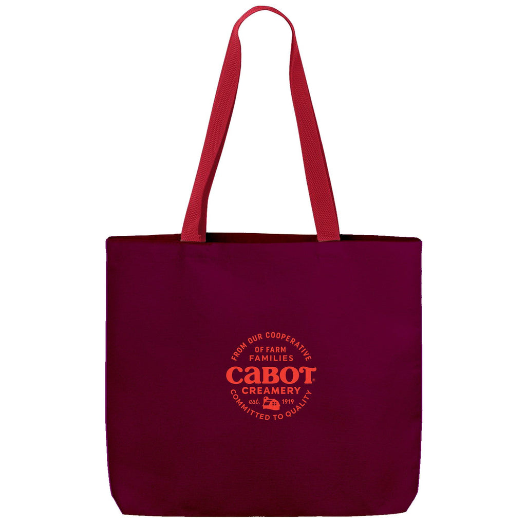 The Making the Cheddar Canvas Tote by New Duds is a sturdy maroon bag with red handles, featuring an orange Cabot Creamery logo and the message: From our cooperative of farm families, Cabot Creamery. Show your co-op pride!.