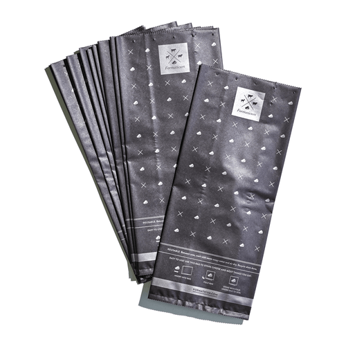 The Formaticum Reusable Cheese Bags feature a dark gray design with white crosses and the freshbake logo. Ideal for cheese lovers, these compostable bags keep your produce fresh and are eco-friendly.