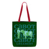 The Cabot Heritage Canvas Tote by New Duds features red handles and Cabot Creamery in bold text, with a charming light green illustration of a farmer and cow, embodying Vermonts rustic beauty.