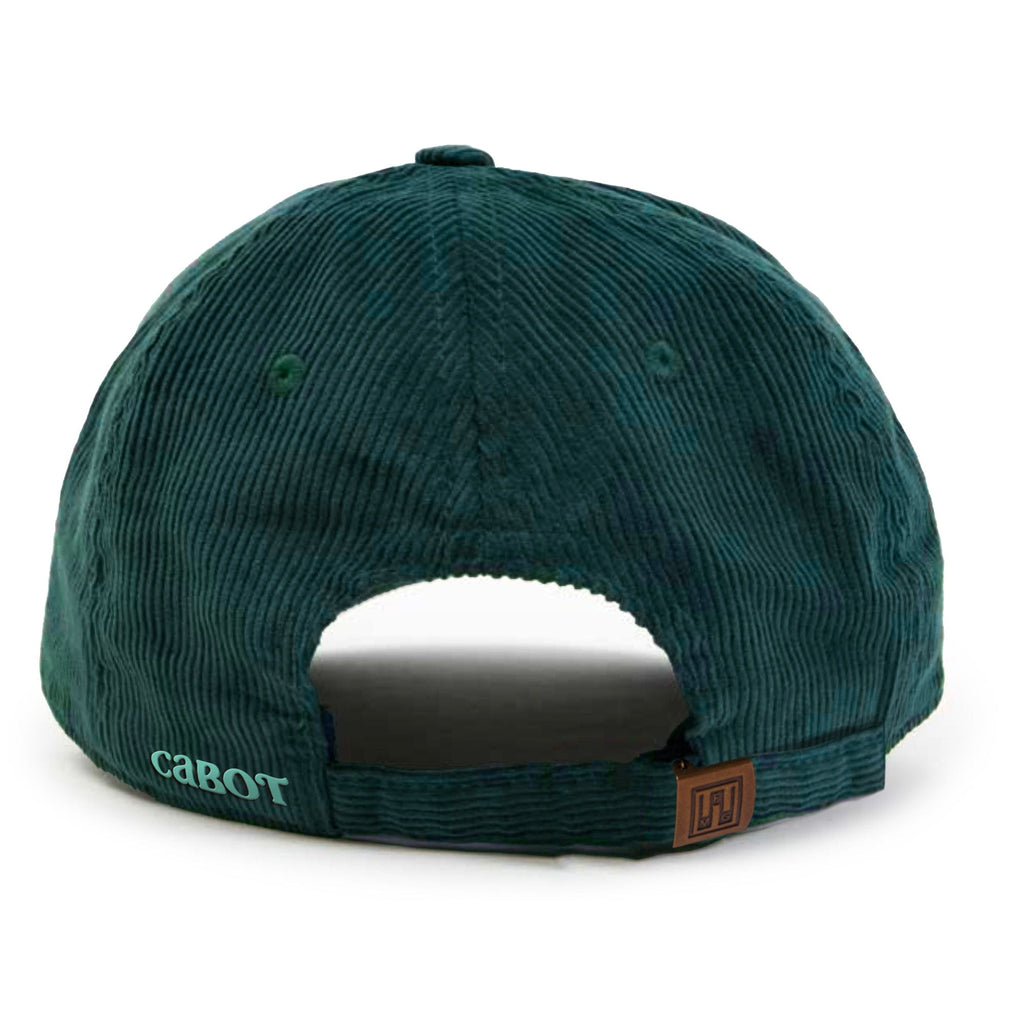 The New Duds Vermont Sharp Chainstitched Corduroy Hat is a dark green five-panel cap, shown from the back, with a brass clasp strap, brown patch, and “caBOT” light blue embroidery on the left side.