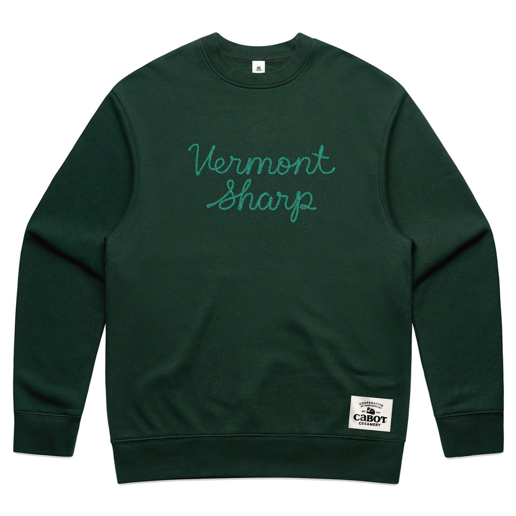 The Vermont Sharp Chainstitched Crewneck by New Duds is a dark green sweatshirt featuring chain-stitched Vermont Sharp lettering and a woven Cabot Creamery patch, made from reclaimed plastic bottles.