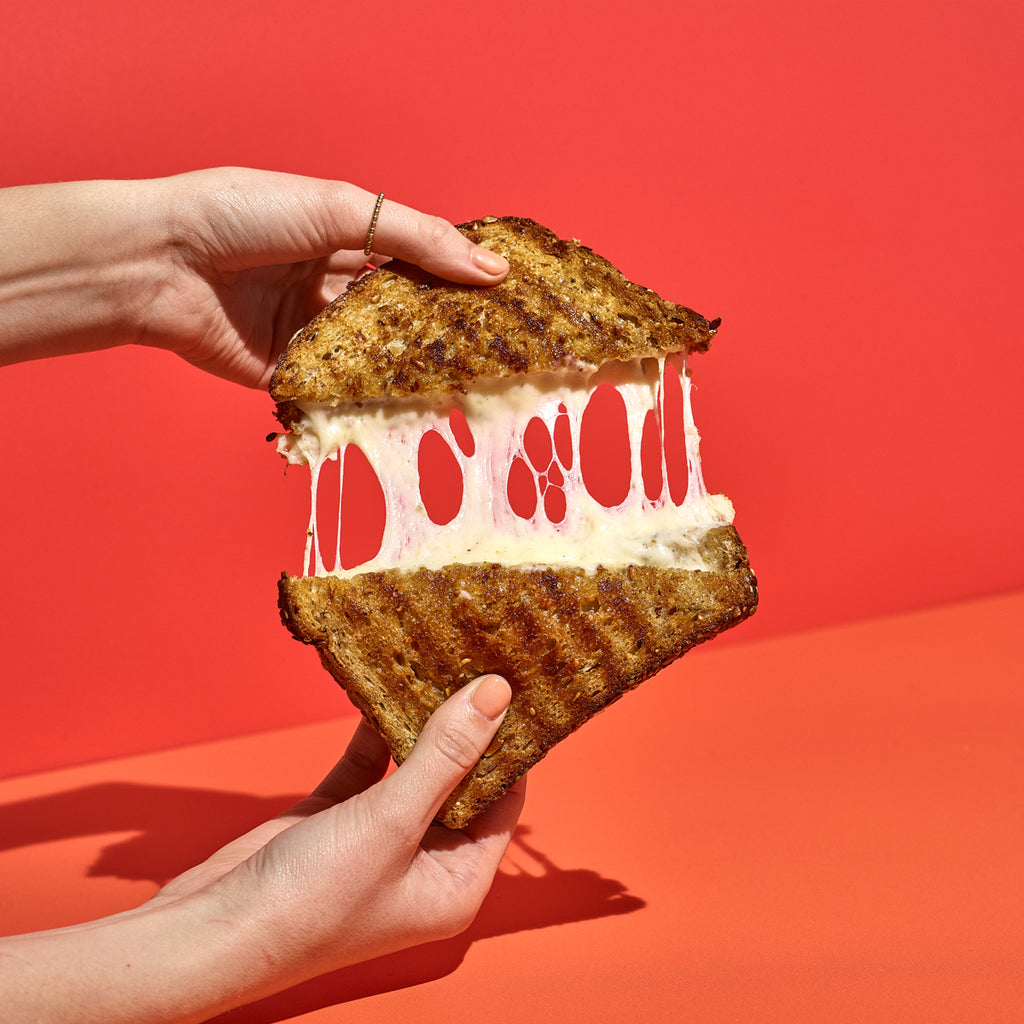 Grilled Cheese pull with hands on a red background