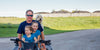 Cabot farmer and grandkids on a 4 wheeler with a dog with farm fields in background.