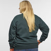A person with long blonde hair faces away, wearing the New Duds Vermont Sharp Chainstitched Crewneck made from reclaimed plastic bottles and blue jeans, set against a plain white background.